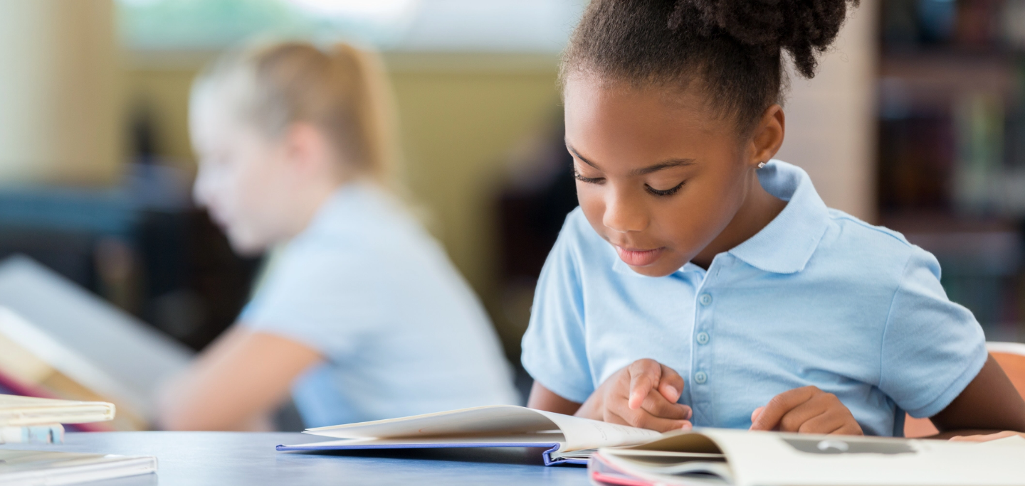 A young girl reading a book in class