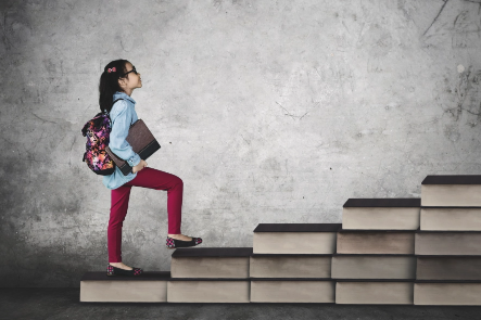 Student going up stairs made of books